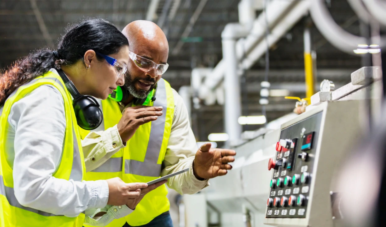 Factory workers analyzing machine controls