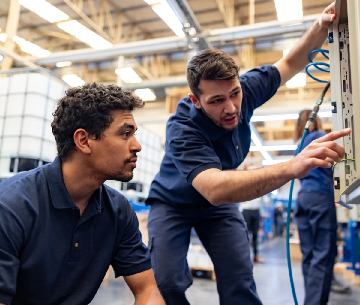 Technicians inspecting machinery in a factory